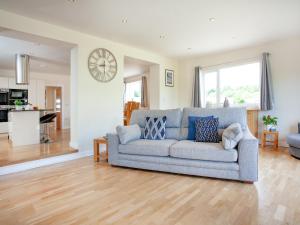 a living room with a gray couch and a kitchen at Sundance in Cheriton Bishop