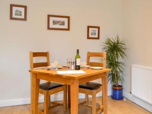 een houten tafel met 2 stoelen en een fles wijn bij Croft Cottage 1 - Uk10587 in Stillington