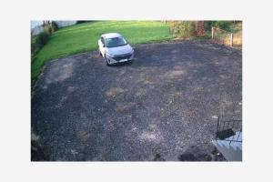 een witte auto geparkeerd op een grindparkeerplaats bij Apartament w Czarnowąsach 2 in Opole