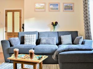 ein blaues Sofa im Wohnzimmer mit einem Tisch in der Unterkunft Quill Corner in Alnwick
