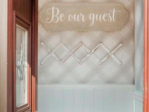 a sign that reads be our guest on a wall at Drumwherry By The Sea in Monreith