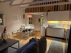 a living room and kitchen with a couch and a table at Cheerful forest cabin Fireplace and Hot tub in Akranes