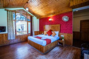 ein Schlafzimmer mit einem Bett und einer roten Wand in der Unterkunft The Northwood Cottages Manali, Mountain View with balcony, near mall road, manali in Manali