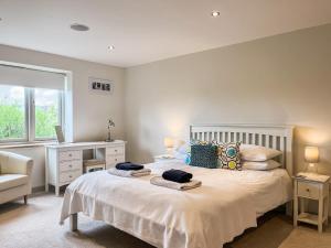 a bedroom with a large white bed with a desk at Springfields in North Wootton +20 photos