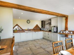 Una cocina con gabinetes blancos y una mesa y sillas. en Orchard Barn - Uk47458, en Chetton