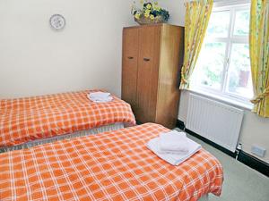 Un dormitorio con una cama naranja y una ventana. en The Coach House, en Wetheral