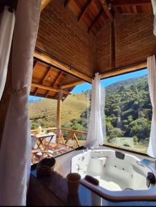 une baignoire dans une pièce avec une grande fenêtre dans l'établissement Chales Estância Verdejante, à Sapucaí-Mirim