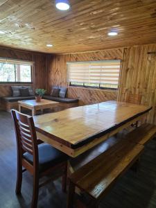 Un comedor con una gran mesa y sillas de madera. en Cabañas Don Agustín Pucón, en Pucón