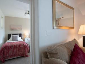 une chambre avec un lit, un miroir et une chaise dans l'établissement Fron - Cottage, à Mynfford