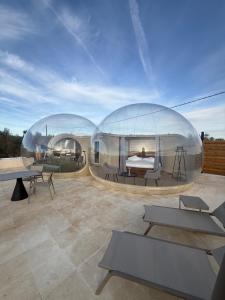two glass domes on a patio with tables and benches at Panoramic Suites Burbuja junto al Puy du Fou y Toledo in Guadamur