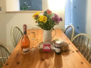 einen Holztisch mit einer Vase aus Blumen und zwei Flaschen in der Unterkunft The Street Cottage in Uley