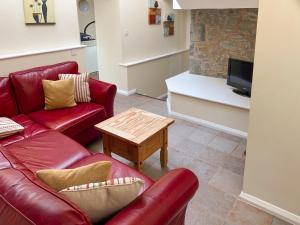 a living room with a red couch and a coffee table at Stable Barn - Hw7591 in Bettws-yn-Rhôs