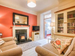 a living room with orange walls and a fireplace at Captain's House in Morfa Nefyn