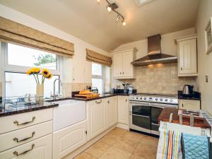 a kitchen with white cabinets and a sink at Captain's House in Morfa Nefyn