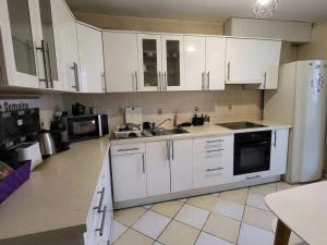 a kitchen with white cabinets and a sink and a refrigerator at Chambre Privée Cosy- Dans Appartement Moderne en Colocation- Tram A -P2-4 in Lormont