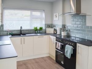 a kitchen with white cabinets and a black stove top oven at Maes Y Mor in Criccieth