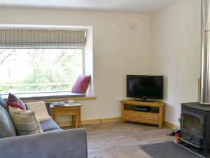 ein Wohnzimmer mit Couch und Flachbildfernseher in der Unterkunft Riverside Cottage in Boreland