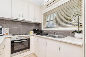 Una cocina con gabinetes blancos y un fregadero y una ventana. en Wagga CBD Apartments, en Wagga Wagga