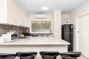 Una cocina con un refrigerador negro y taburetes negros. en Wagga CBD Apartments, en Wagga Wagga