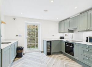 a large kitchen with green cabinets and a window at Elegant 3-Bed Near Station, Pantiles & Calverley in Royal Tunbridge Wells