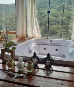 a bath tub sitting in a room with a window at Chales Estância Verdejante in Sapucaí-Mirim +40 photos