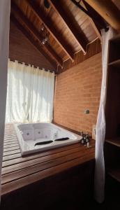 a large white tub in a room with a window at Chales Estância Verdejante in Sapucaí-Mirim