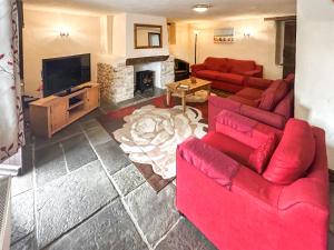 a living room with red couches and a fireplace at Cider Cottage in Hawkchurch