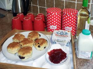 a tray with a plate of pastries and jam and milk at Cider Cottage in Hawkchurch +18 photos