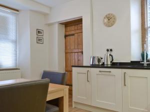 a kitchen with a table and a clock on the wall at Bede's Cottage in Windermere