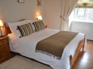 a bedroom with a large white bed with two pillows at Bede's Cottage in Windermere