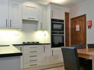 a kitchen with white cabinets and a wooden table at Bede's Cottage in Windermere
