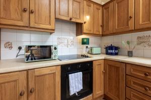 a kitchen with wooden cabinets and a microwave oven at Ballyneill Farmhouse in Carrick-on-Suir +33 photos