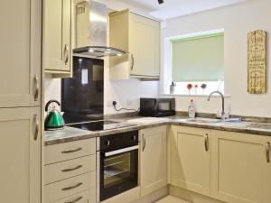 a kitchen with white cabinets and a stove top oven at Scullery Cottage in Penrhyn Bay