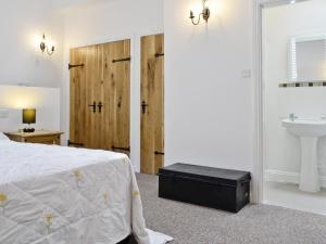 a bedroom with a bed and a sink and a bathroom at Scullery Cottage in Penrhyn Bay