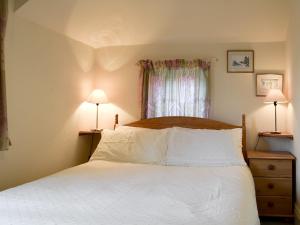 a bedroom with a bed with white sheets and a window at Oaklands in Ambleside