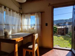 a table and chair in a room with a window at KUNTUR 2 Cabañas in El Chalten