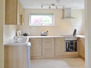 a kitchen with wooden cabinets and a sink and a window at Watersmeet in Looe