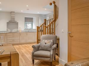 Una sala de estar con una silla y una cocina. en The Old Mill, en Linlithgow