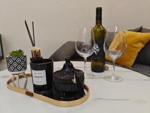 a tray with wine glasses and wine bottles on a table at Kerkétio guesthouse in Tríkala