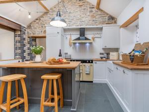a kitchen with white cabinets and wooden stools at Cwtch Ty Gwyn in Llandeilo