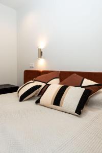 Una cama con almohadas blancas y negras. en Apartamentos Máximo, en Mérida