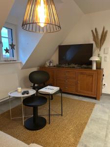 a living room with two chairs and a flat screen tv at Charmant appartement avec vue sur les vignes in Ammerschwihr