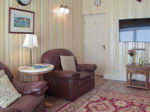 ein Wohnzimmer mit einer Couch, einem Sessel und einem Tisch in der Unterkunft Carthouse Cottage in Carew