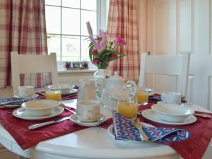 einen Tisch mit Teller, Tassen und Gläsern Orangensaft in der Unterkunft Carthouse Cottage in Carew