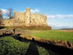ein altes Schloss mit einer Brücke auf einem Feld in der Unterkunft Coast View Cottage - Hw7745 in Pendine + 2 Fotos