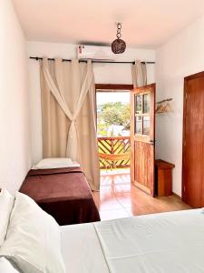 a bedroom with two beds and a door to a balcony at Pousada Real Cipo in Serra do Cipo
