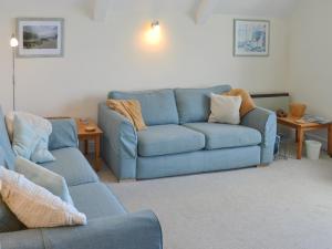 ein Wohnzimmer mit einem blauen Sofa und 2 Stühlen in der Unterkunft Spindrift in Coverack