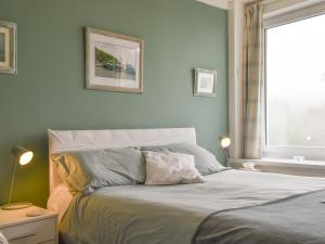 ein Schlafzimmer mit einem Bett mit zwei Lampen und einem Fenster in der Unterkunft Spindrift in Coverack