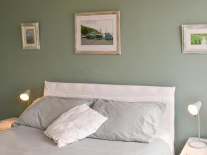 ein weißes Bett mit zwei Kissen und zwei Bildern an der Wand in der Unterkunft Spindrift in Coverack + 16 Fotos
