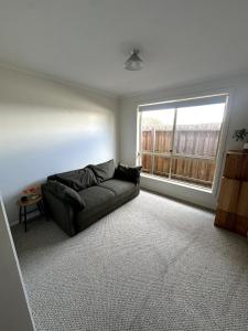 a living room with a couch and a window at Beach Escape Torquay in Torquay